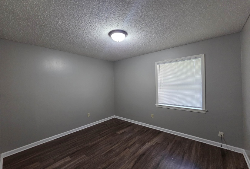 Empty room with dark wood finished floors and a textured ceiling