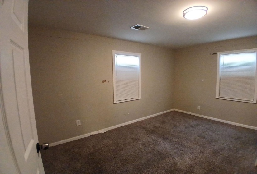 Carpeted room featuring two windows with horizontal blinds, a white ceiling, and a flush-mount light fixture