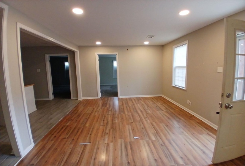 Spacious room featuring rich wood-finish flooring, recessed lighting, and a neutral wall palette
