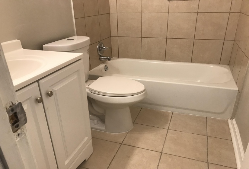 Bathroom featuring light tile patterned floors, vanity, and  shower combination