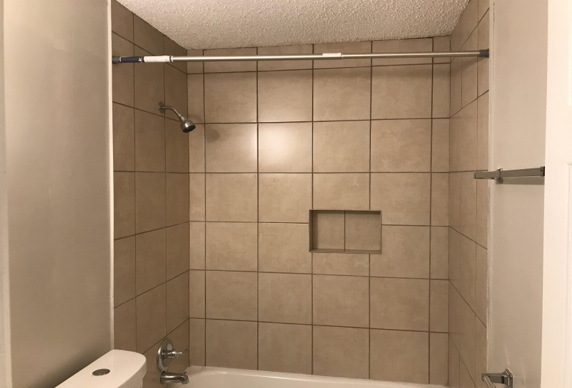 Full bath with bathing tub / shower combination and a textured ceiling