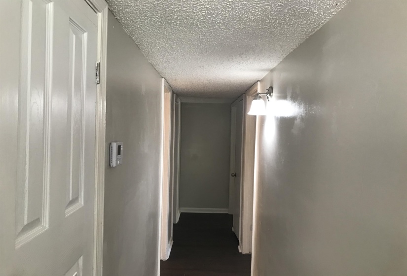 Corridor featuring a textured ceiling and dark wood-type flooring