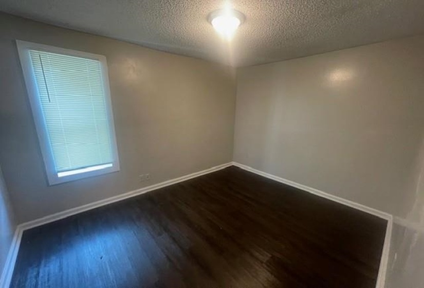 Spare room featuring a textured ceiling and dark wood finished floors