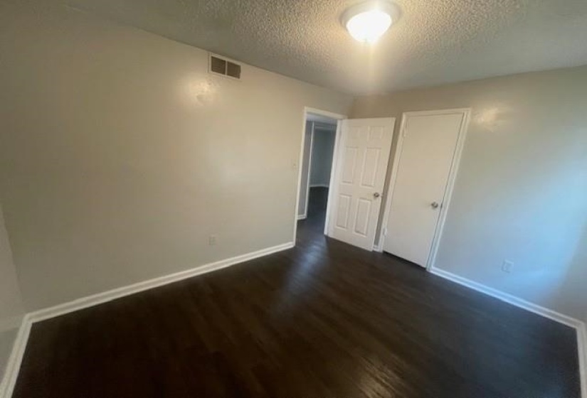 Unfurnished bedroom with dark wood finished floors, a textured ceiling, and a closet