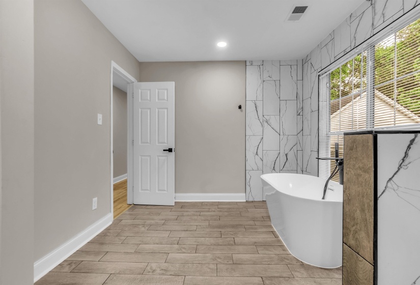 Full bathroom with a freestanding tub, wood finish floors, tile walls, and recessed lighting