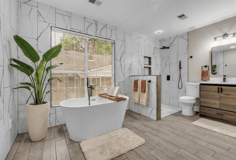 Full bath featuring vanity, a marble finish shower, a freestanding bath, tile walls, and light wood-style flooring
