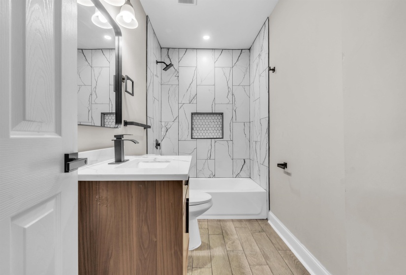 Bathroom with tub / shower combination, vanity, and wood finish floors