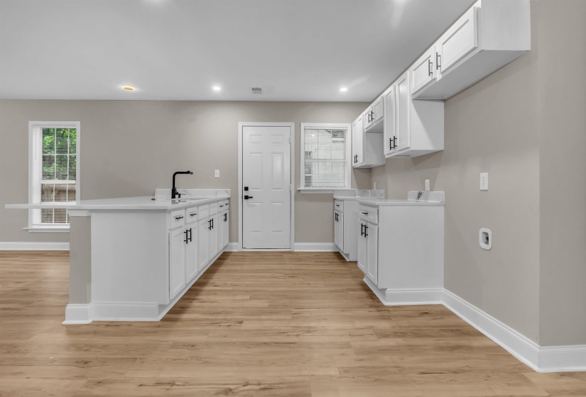 Kitchen with a peninsula, white cabinetry, light wood-style flooring, and recessed lighting
