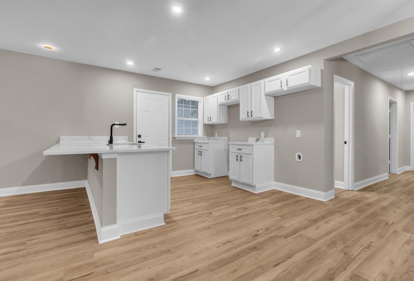 Kitchen featuring a kitchen bar, white cabinetry, a peninsula, recessed lighting, and light wood-style floors