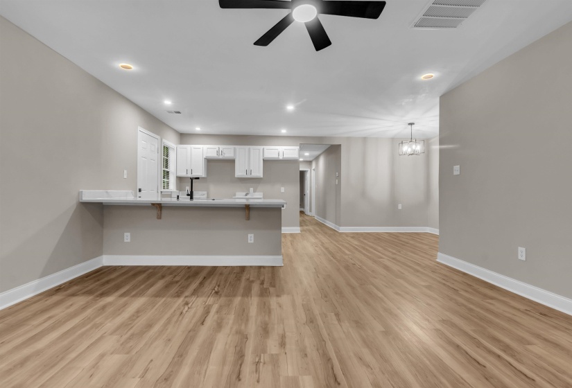 Unfurnished living room featuring a ceiling fan, light wood finished floors, and hanging lights