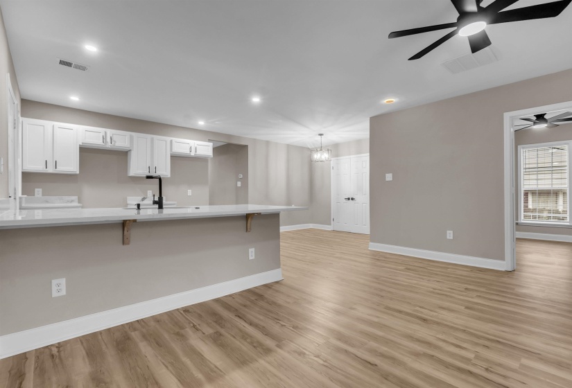 Kitchen with a breakfast bar, light wood finished floors, white cabinets, ceiling fan, and suspended lighting