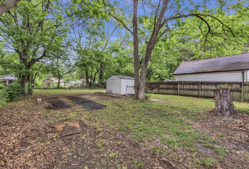 Fenced backyard featuring a shed