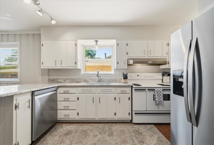 Kitchen featuring white cabinetry with silver hardware, light-toned countertops, and a stainless steel dishwasher