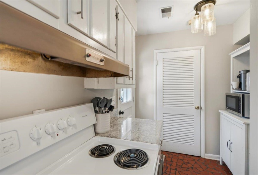 Kitchen featuring an electric range, granite-style countertop, white cabinetry, and a louvered door