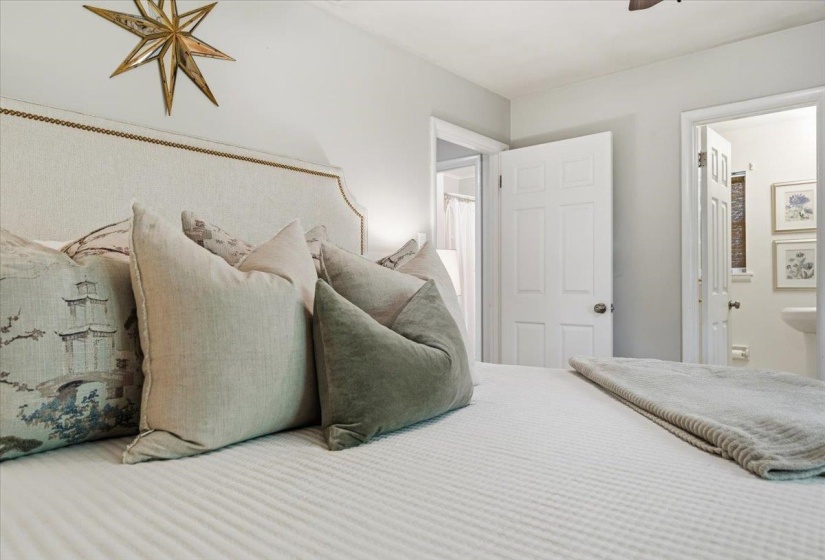 Bedroom featuring a fabric upholstered headboard with nailhead trim, white paneled doors, and light-colored walls