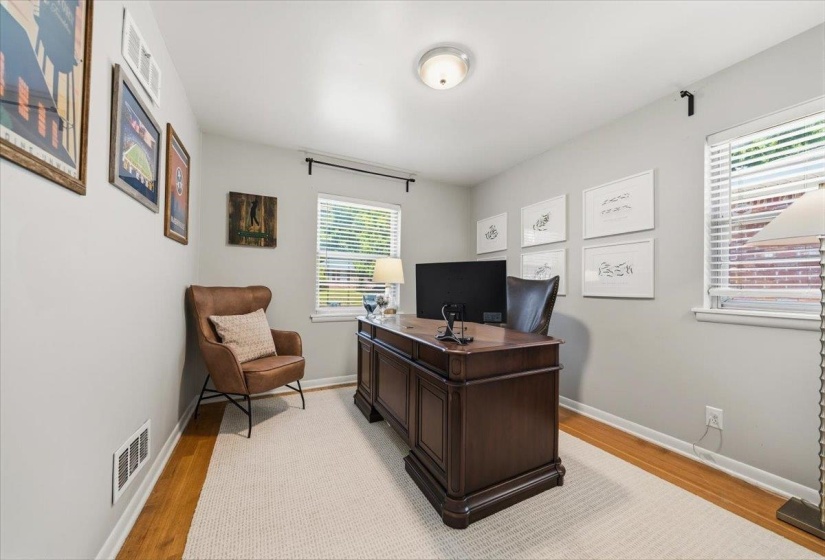 Hardwood flooring with a light-toned area rug, neutral wall paint, and white trim molding