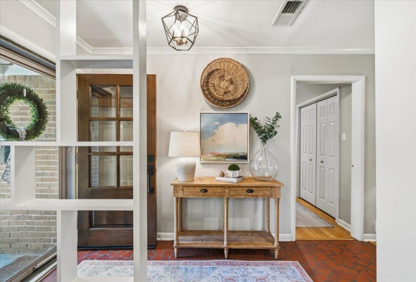 Entryway featuring terracotta-style flooring, a wood-panel door with glass inserts, and a geometric flush-mount light fixture