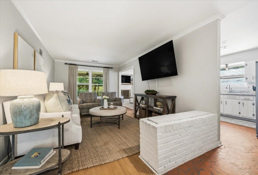 Living area featuring light wall paint, crown molding, wood-finish flooring, and a white painted brick half-wall