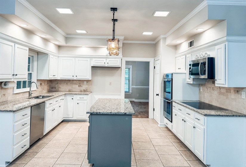 Bright kitchen featuring white cabinetry and light-colored granite countertops