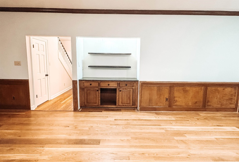 Hardwood flooring throughout featuring a built-in cabinet with a stone-finish countertop and floating shelves