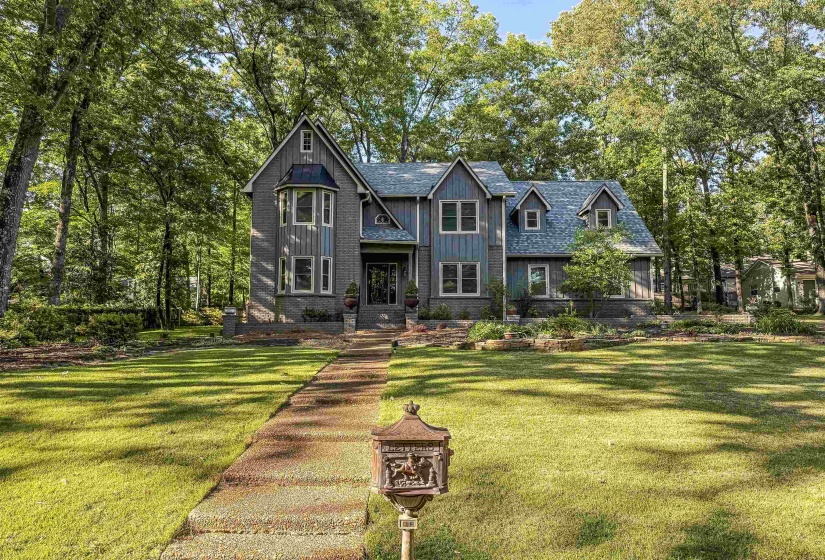 Gable-roof property featuring a prominent bay window, varied facade materials including brick and horizontal siding, and multiple dormer windows