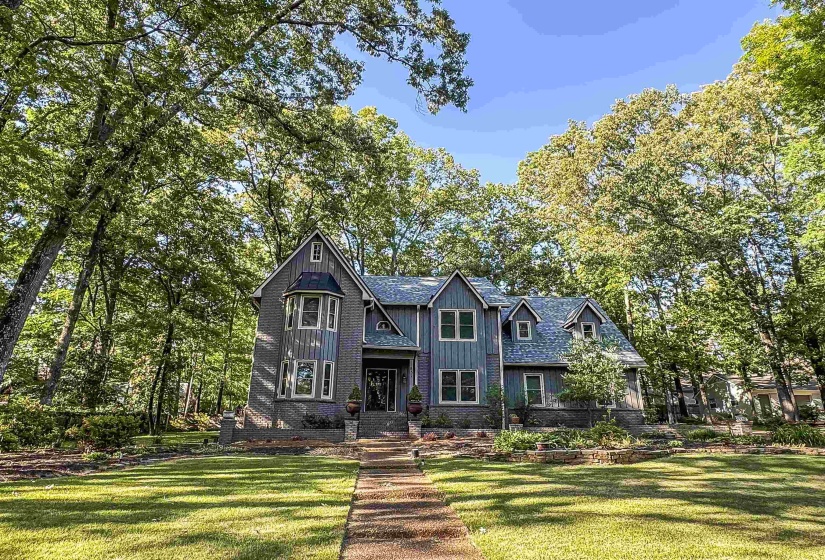 Gable-roof residence featuring mixed material siding, a stone facade, and dormer windows