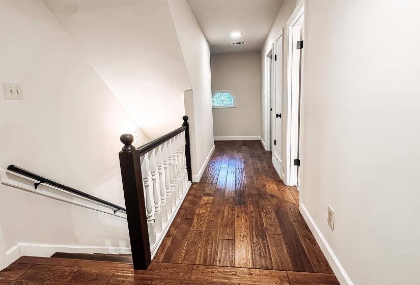 Hallway with wood-finish flooring, white walls, and white trim