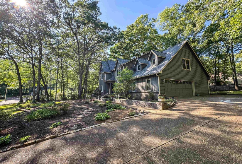 Crafted exterior featuring green siding, a steeply pitched roof, dormer windows, and an attached two-car garage