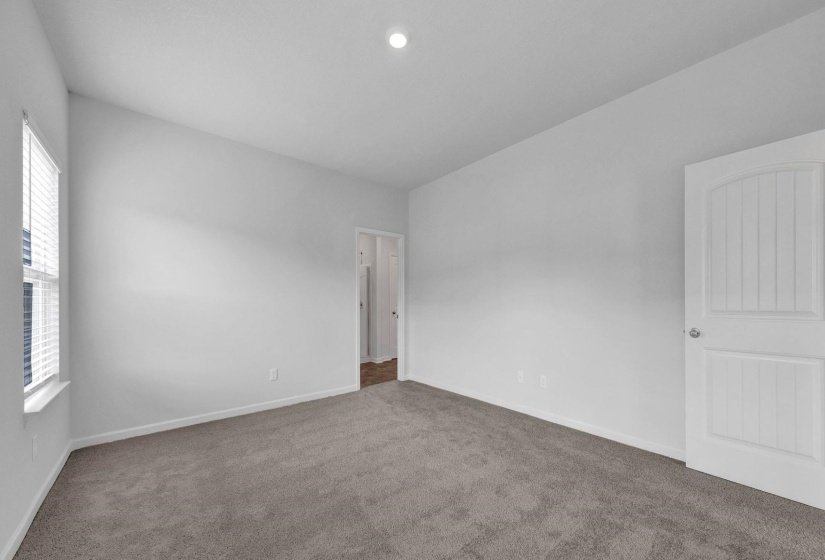 Spacious interior room featuring a vaulted ceiling, recessed lighting, and soft grey carpeting