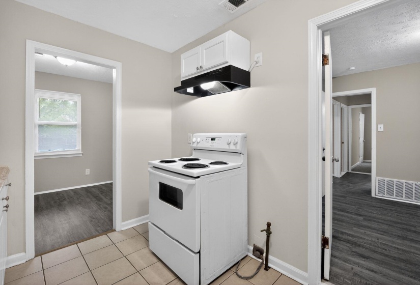 Kitchen featuring a white electric range with an overhead vent hood and white cabinetry