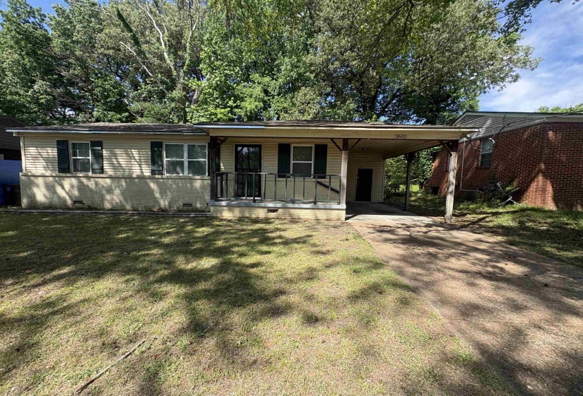 Single-story residence featuring a covered front porch with black railings, a paved carport, and a concrete driveway