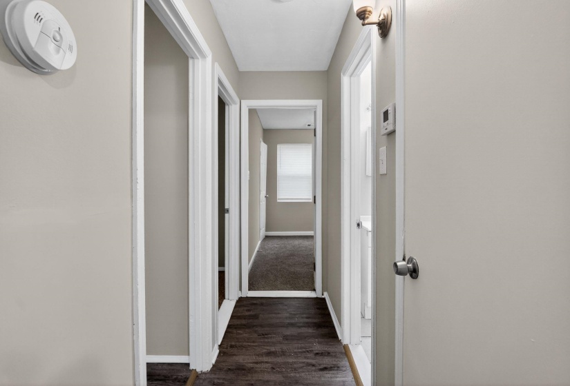 Hallway featuring wood-finish flooring, light neutral wall paint, and white trim