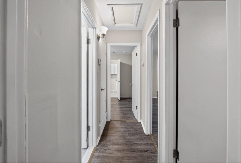 Hallway with wood-finish flooring, white walls, and white trim