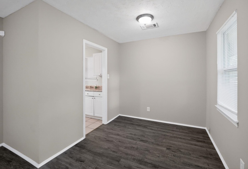Interior room featuring wood-finish flooring, light grey painted walls, and a window with blinds