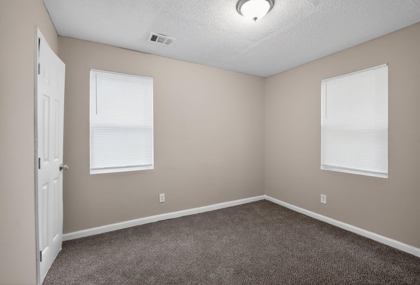 Carpeted room featuring two windows with horizontal blinds, light tan wall paint, and white trim