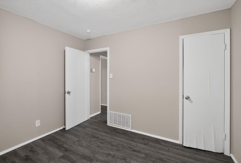 Neutral-toned room featuring dark wood-finish flooring, white baseboards, and a textured ceiling