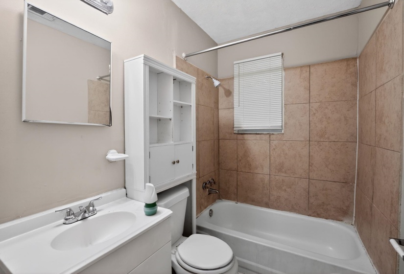 Bathroom featuring a white vanity with integrated sink, chrome faucet, wall-mounted mirror, and overhead lighting