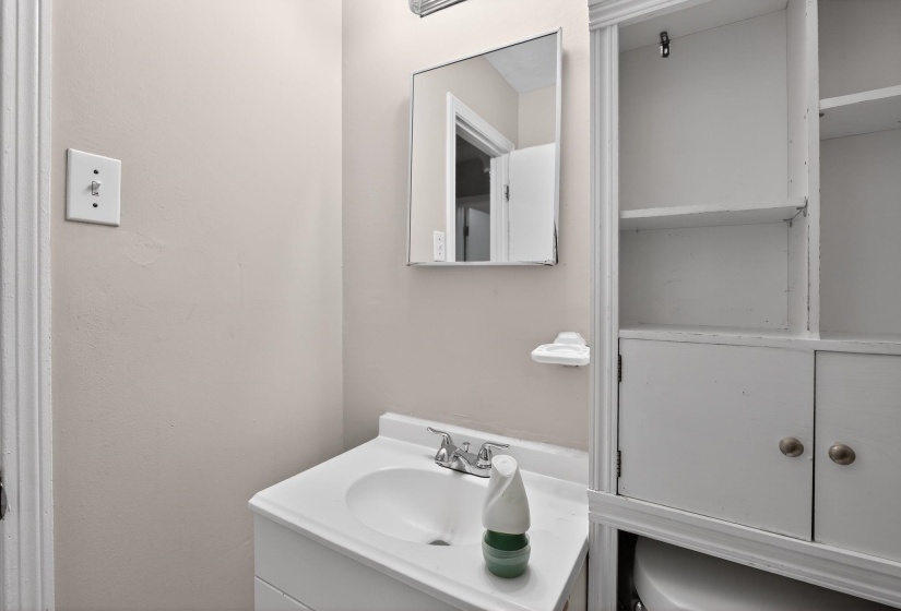 Bathroom vanity with an integrated white sink, chrome faucet, and mirrored medicine cabinet