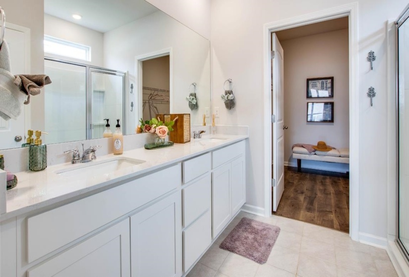 Double vanity featuring white cabinetry, integrated sinks, chrome fixtures, and a large wall-mounted mirror