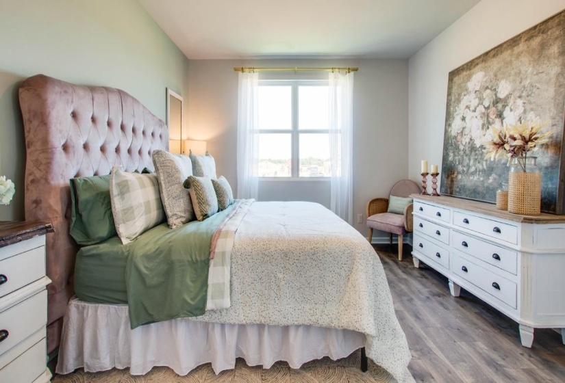 Spacious room featuring wood-finish flooring, a multi-pane window, and a light color palette