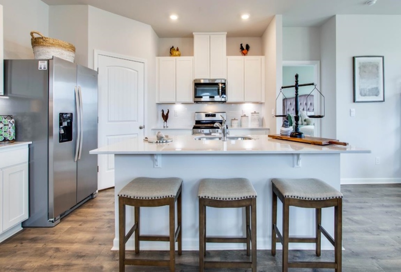 Kitchen featuring an expansive center island with seating, white cabinetry, stainless steel appliances, wood-finish flooring, and recessed lighting