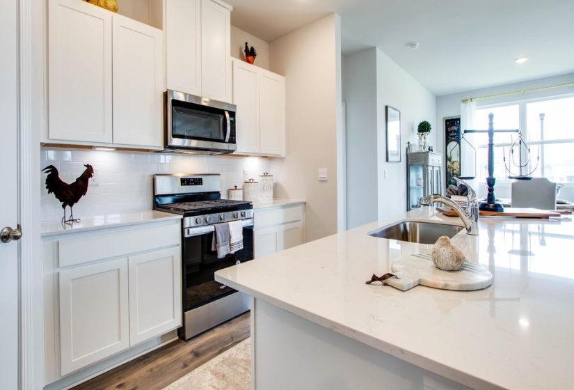 Modern kitchen featuring white shaker cabinetry, stainless steel appliances, a subway tile backsplash, and a large island with an undermount sink