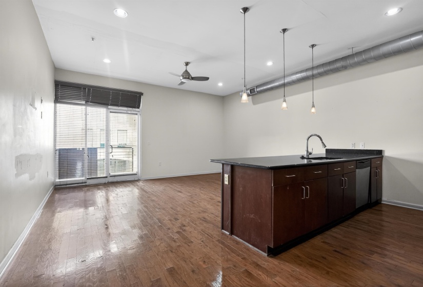 Kitchen island featuring a dark countertop, undermount sink, and stainless steel dishwasher