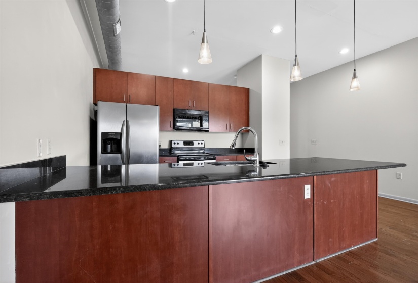 Kitchen with wood-finish cabinetry, dark stone countertops, and stainless steel appliances