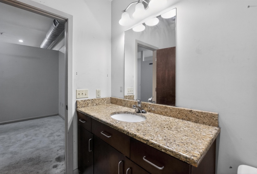 Bathroom vanity featuring a speckled countertop, integrated sink, and dark wood cabinetry with brushed nickel hardware