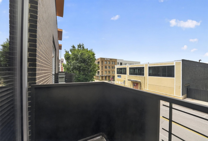 Private balcony with dark gray railing and composite decking, offering urban surroundings