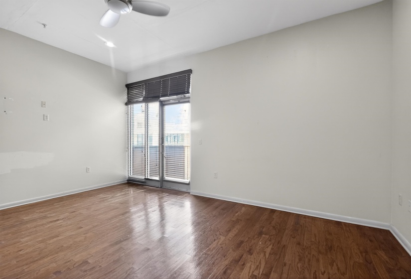 Spacious room featuring wood-finish flooring, light-toned walls, and a ceiling fan