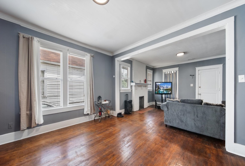 Living area featuring wood-finish flooring, white trim, recessed lighting, and a white-painted brick fireplace