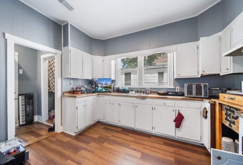 Kitchen featuring wood-finish flooring, white cabinetry, light-toned countertops, and painted panel walls