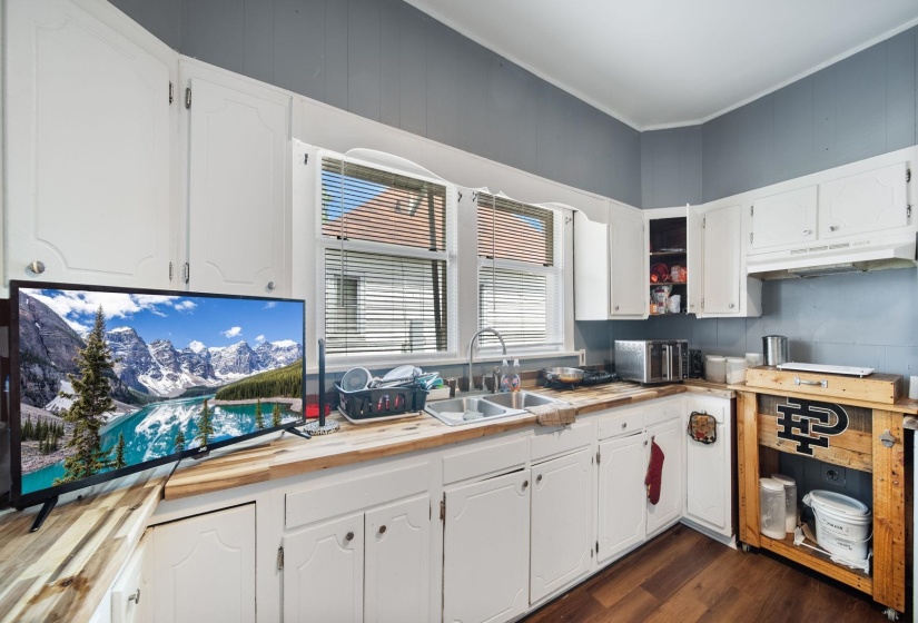 Kitchen featuring white cabinetry with brushed nickel hardware, wood-finish countertops, and wood-finish flooring
